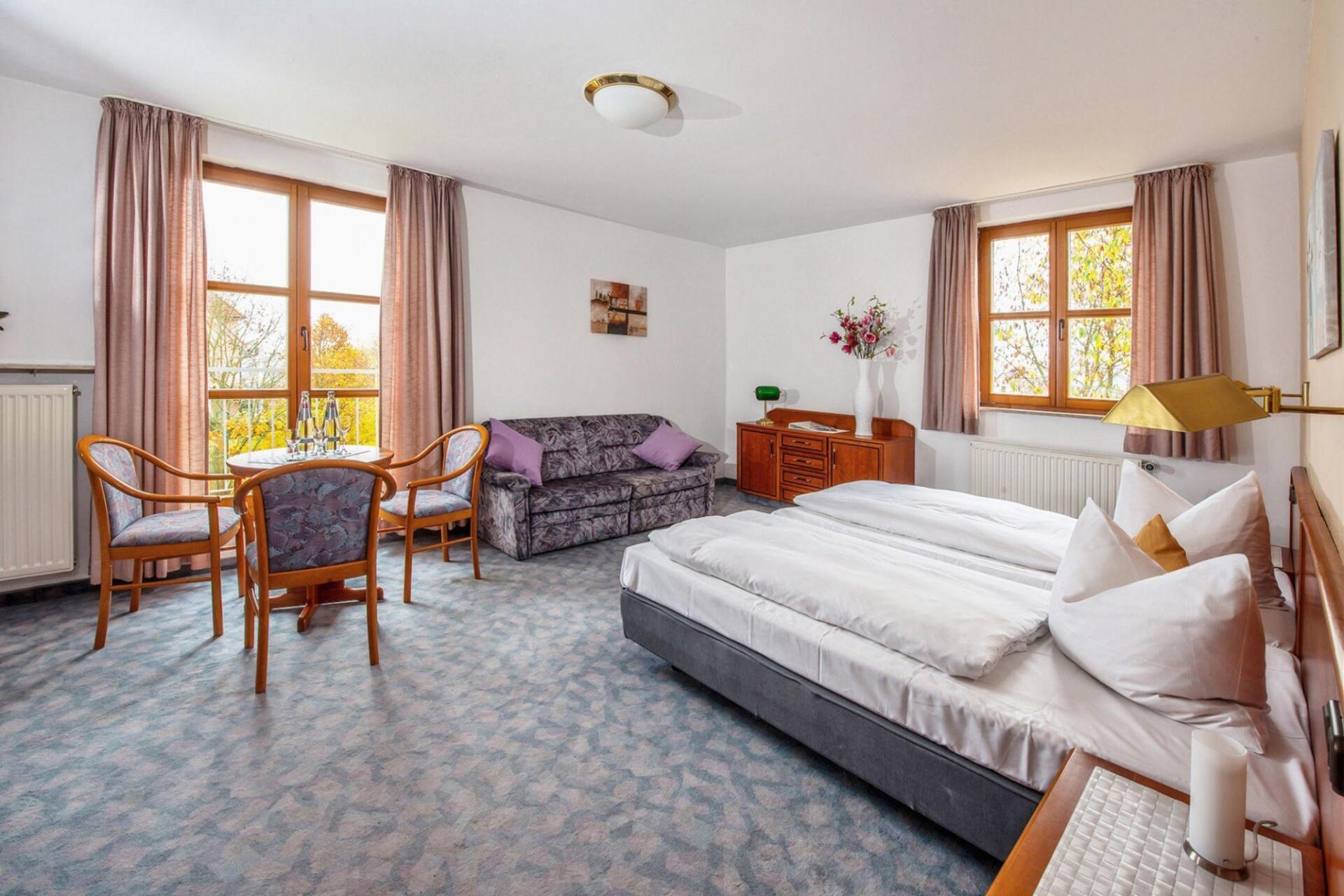 Doppelzimmer des Hotel Rhönblick, geschmackvoll Eingerichtet mit Gästestühlen, einer Couchgarnitur, Lampen und einem TV Gerät