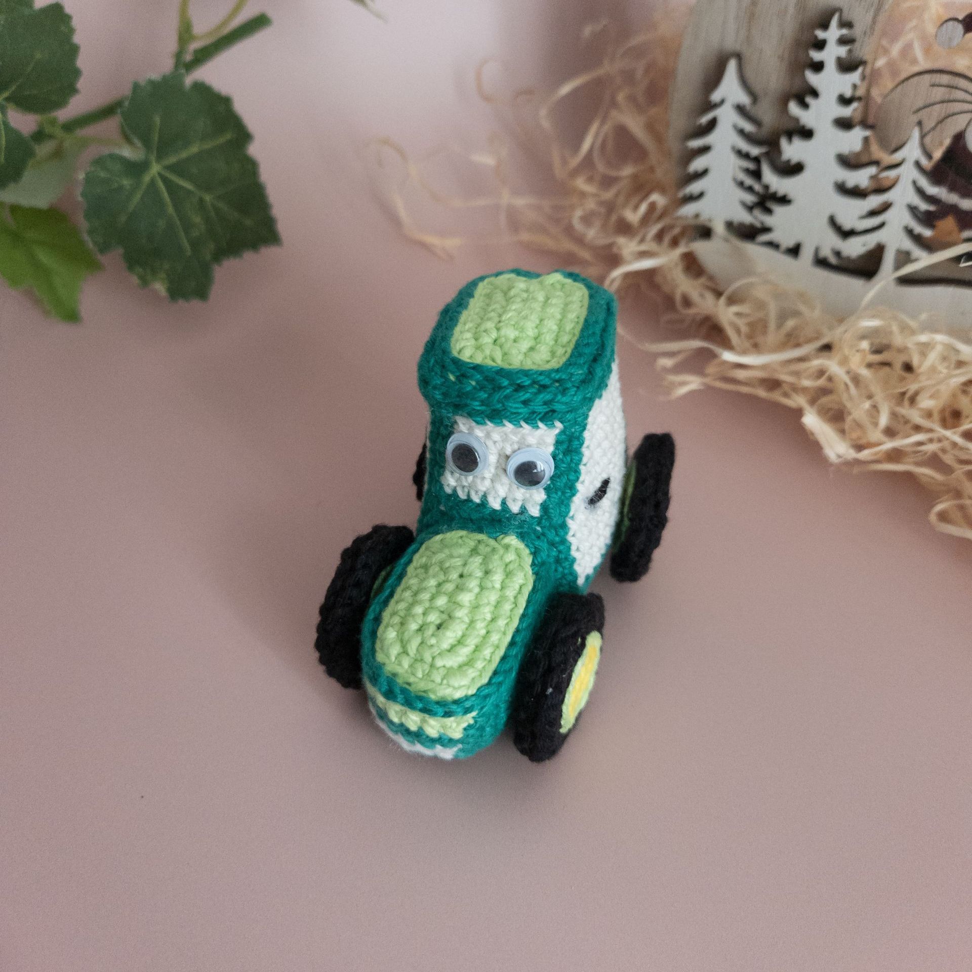 Tracteur vert sapin et vert clair , sa cabine est composée de 4 vitres dont le pare brise de couleur blanc cassé. Des yeux de sécurité donne un aspect dessin animé à l'ouvrage. Ce mignon tracteur au crochet tient dans une main adulte, il est souple et solide à la fois