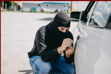 Photo of a hooded man bent down beside a car, picking it's lock. Photo linked to ContactNok.com TagaBike