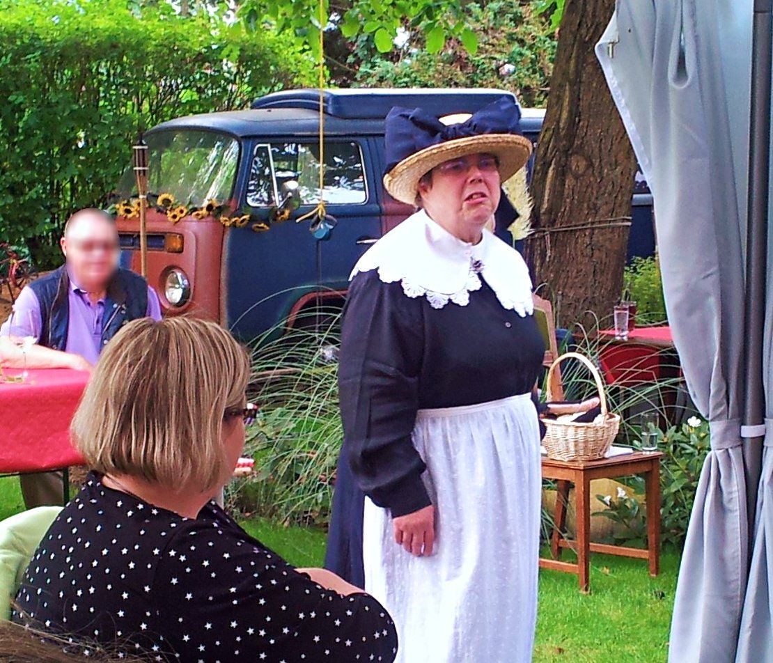 Bremer Deern im Garten des Café Törtchen, Strohhut mit großer blauer Schleife, langer blauer Rock, weiße Schürze, breiter weißer Kragen, Photo Britta Ogasahara©