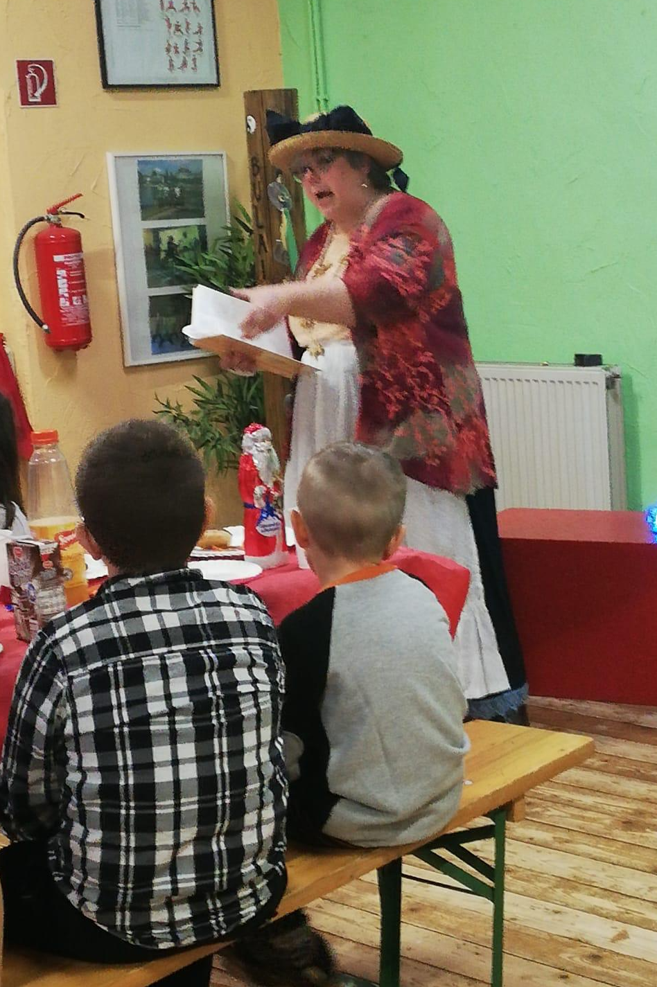 Ich lese aus einem Buch die Geschichte vom Schneemann, Kostüm blauer Rock mit weißer Schürze, Strohhut mit blauer Schleife,