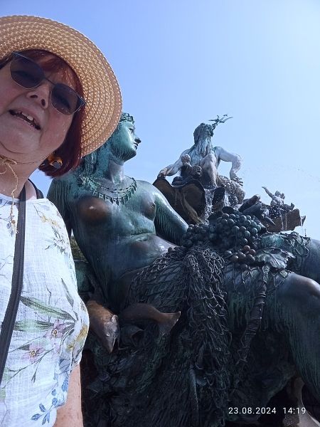 Selfie vor einer Fischerin aus Bronze im Hintergrund Neptun tront über allem.