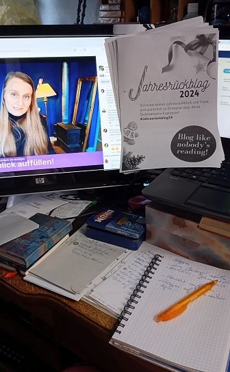 WB Jahresrückblog 2024, im Monitor ist Judith Peters zu sehen, Notizbuch mit Kugelschreiber