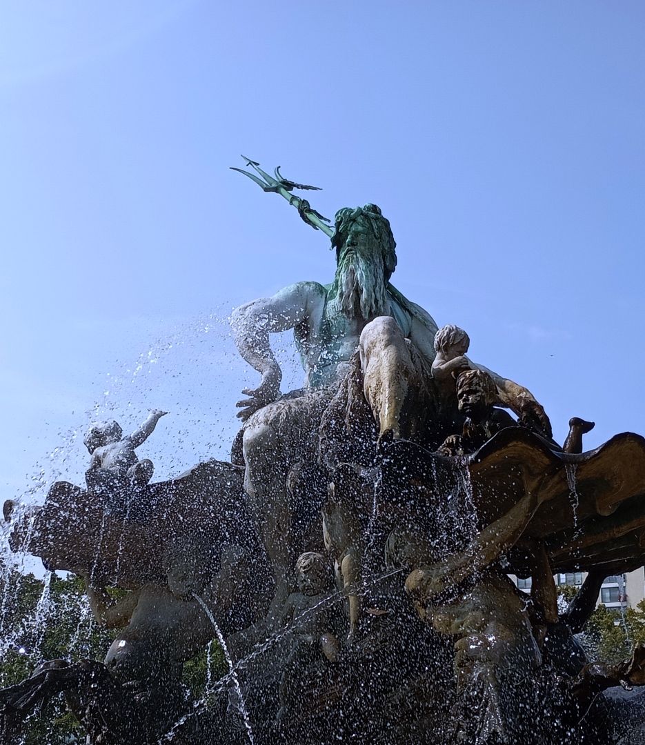 Neptun sitzt auf einer Muschel und viele kleine Kinder sind um ihn rum.