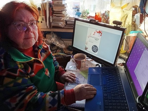 Britta sitzt am Schreibtisch, darauf ein Monitor und in Laptop