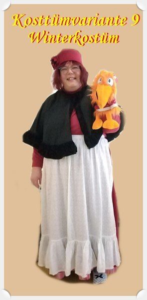 roter langer Rock, weiße Schürze, roter Pullover, schwarze Pelerine, roter Wollhut, sowie eine Handpuppe
