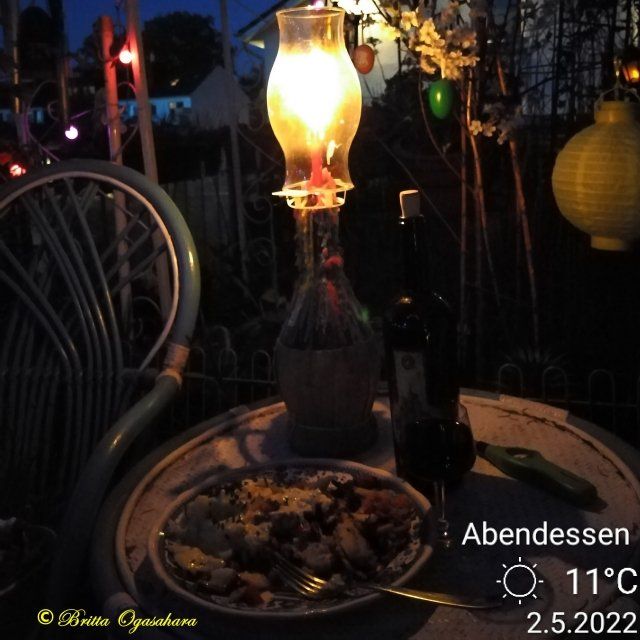 An einem lauschigen Sommerabend, Abendessen auf dem Balkon mit einem Glas Rotweinbei Kerzenschein. Windlicht, Kerzeenlicht, Rotweinflasche, Abendessen, Glas Rotwein
