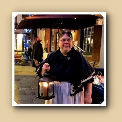 Fisch Luzie in Kostüm, blaue Bluse, blauer Umhang, weiße Schürze, Kerze in der Hand,