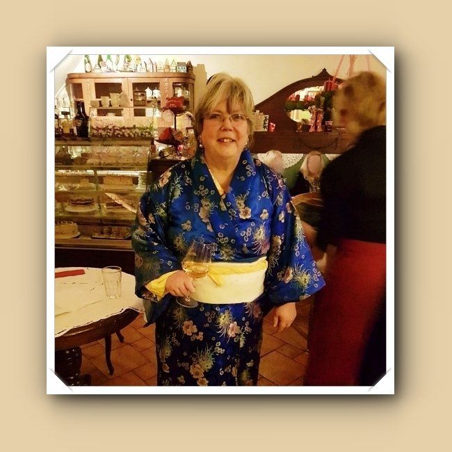 blauer Kimono mit gelben Obi, im Hintergrund kann man die Kuchenvitrine des Café Törtchen erkennen