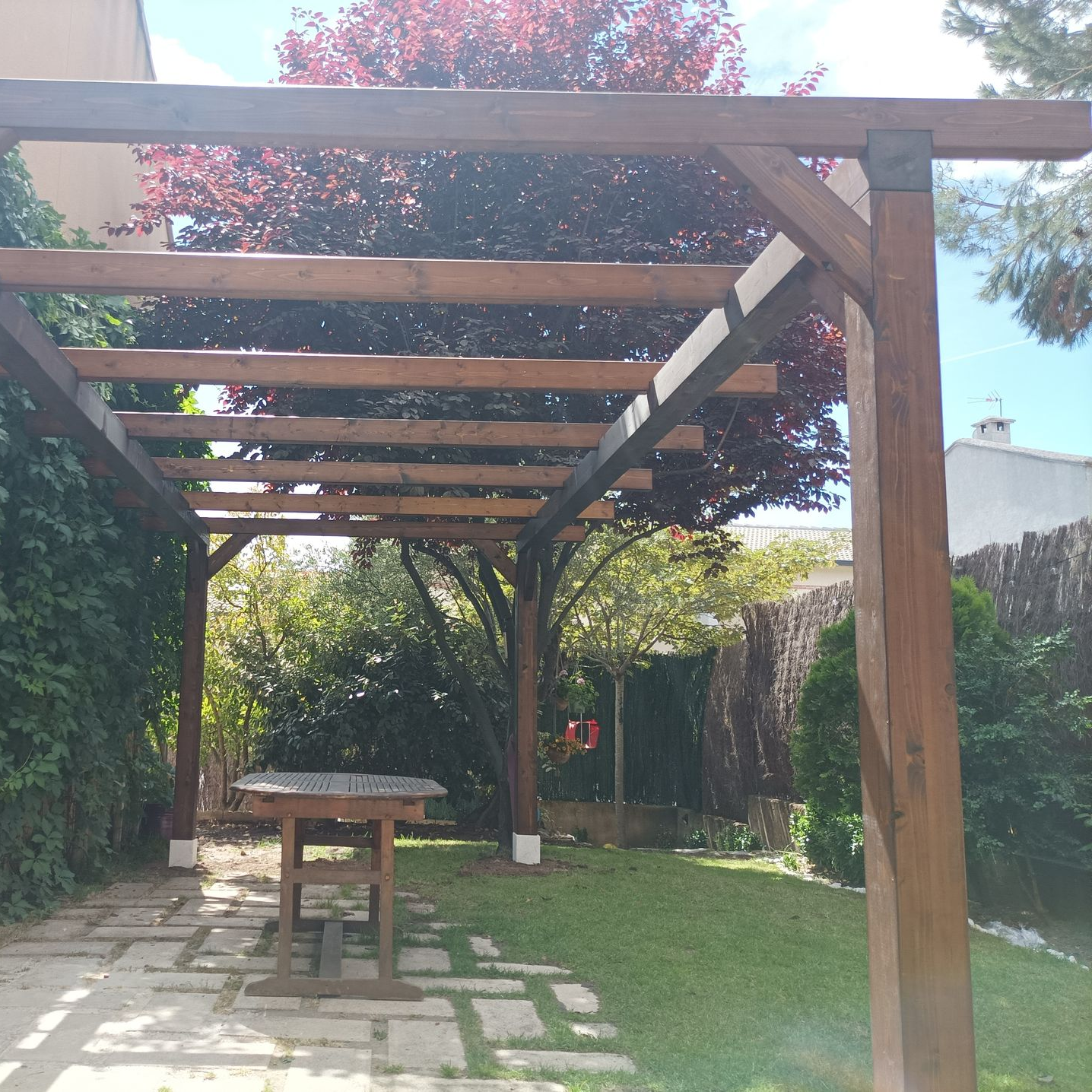 Pérgola clásica integrada en un jardín con vegetación