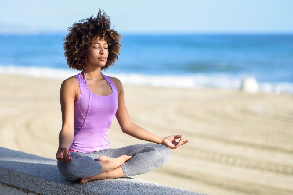 woman meditating on the beach