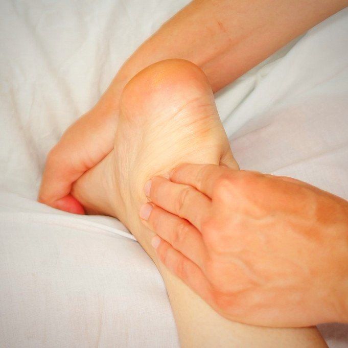 die rechte Fußunterseite eines Kindes wird mit einer Hand oberhalb des Sprunggelenks fixiert und mit der anderen Hand abgetastet