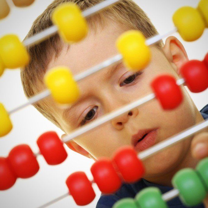 ein Junge sitzt hinter einem Rechenschieber