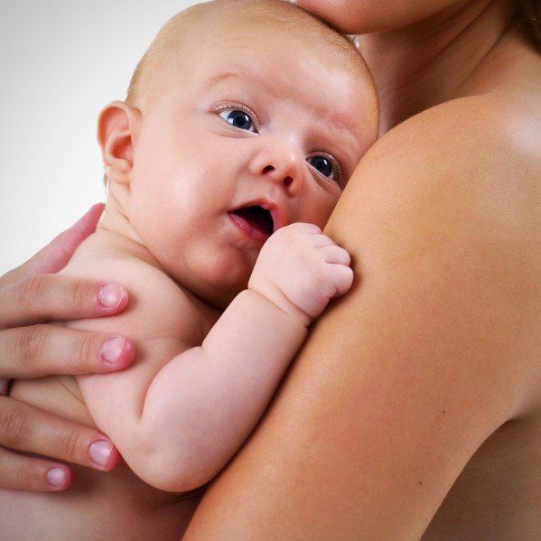 ein Säugling liegt auf dem Arm eines Erwachsenen