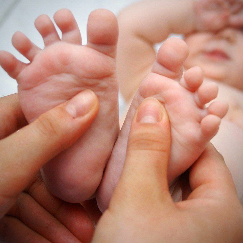 Die rechte und linke Fußsohle eines Säuglings wird jeweils mit dem Daumen abgetastet