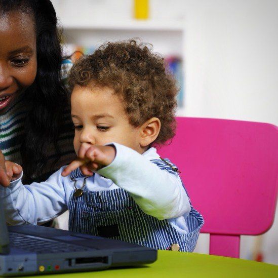 ein Kleinkind zeigt auf die Tastatur von einem Laptop
