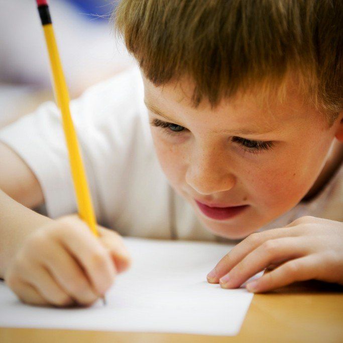 ein Junge schreibt mit der rechten Hand auf Papier