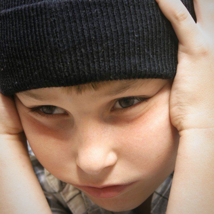 ein Kind hält sich mit seinen Händen die Ohren zu