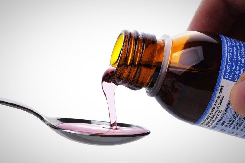 auf einen Löffel wird Fiebersaft aus einer Flasche geleert