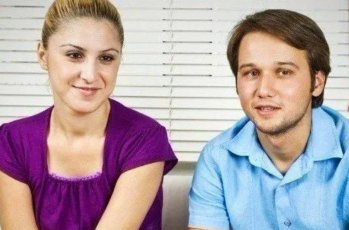 eine junge Frau sitzt neben einem jungen Mann und hören einer dritten Person, die nicht im Bild zu sehen ist, zu