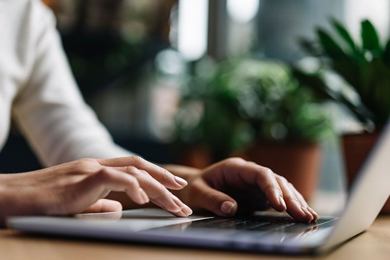 Frauenhand tippt auf Laptop Tastatur