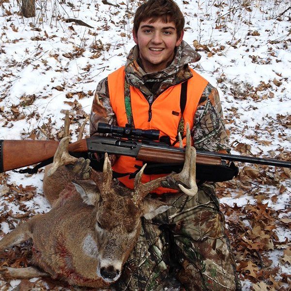 boy kneeling with a buck he shot