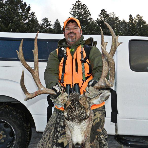 Hunter standing in front of a white truck with a deer