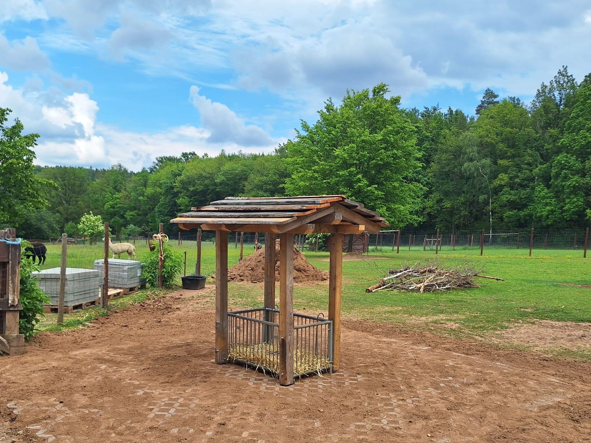 Eine schöne neue überdachte Futterraufe steht auf dem befestigten Untergrund.