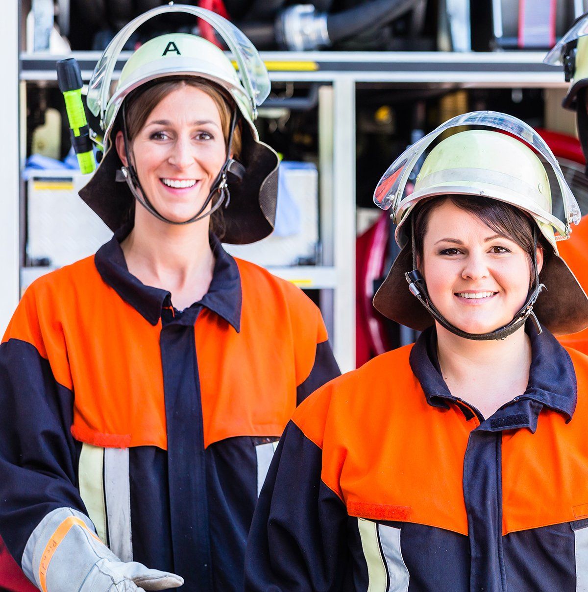 Das Bild zeigt zwei Feuerwehrfrauen in Einsatzkleidung.