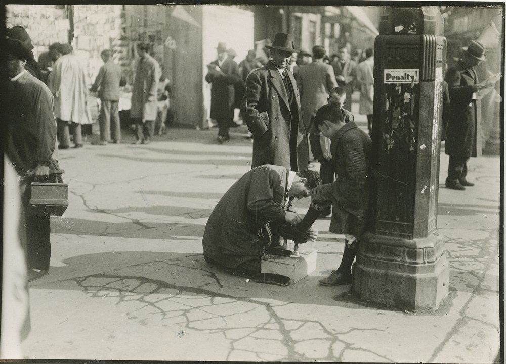 Un limpiabotas sacando brillo a los zapatos de un niño (1933)