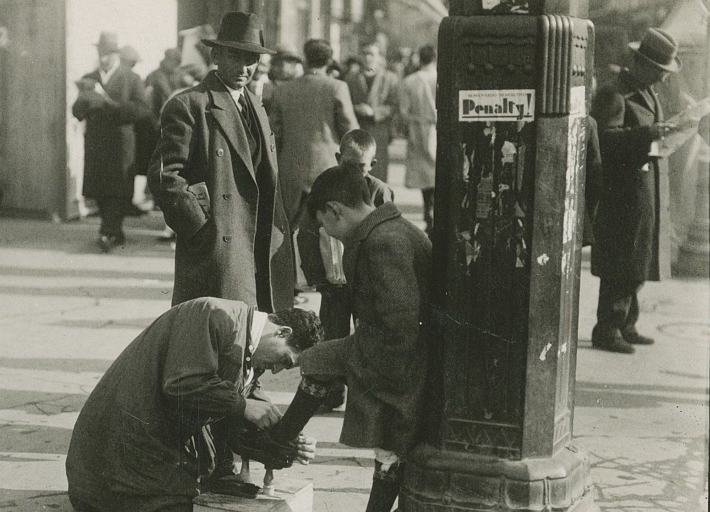 Un limpiabotas sacando brillo a los zapatos de un niño (1933)