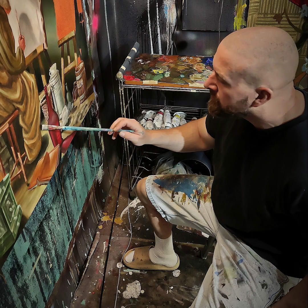 Der zeitgenössische Künstler Drew Camell bei der Arbeit in seinem Atelier. Detailreiche Malerei auf Leinwand im Entstehungsprozess. Fokus auf künstlerische Technik, Handwerk und die Materialität der Farbe in einer authentischen Studio-Umgebung.