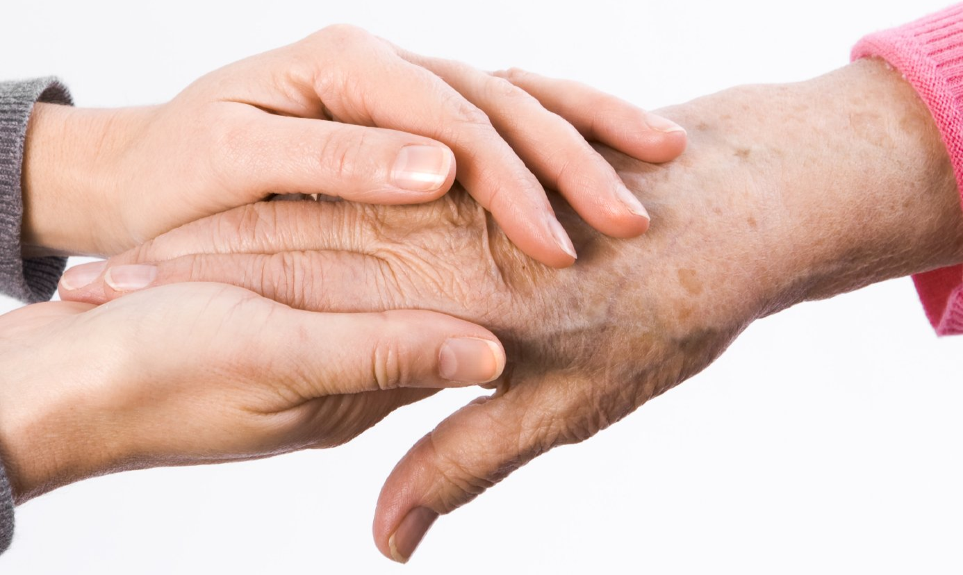 Ihr Buch kann trösten. Jüngere Frau umschließt die Hand einer älteren Frau mit ihren Händen