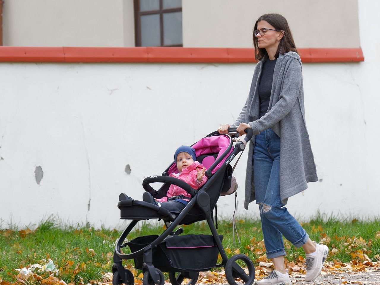 Eine Mutter, die ihr kleines Kind in einer Kinderkarre spazieren schiebt.
