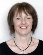 Head and shoulders image of a woman with dark hair wearing dark clothing