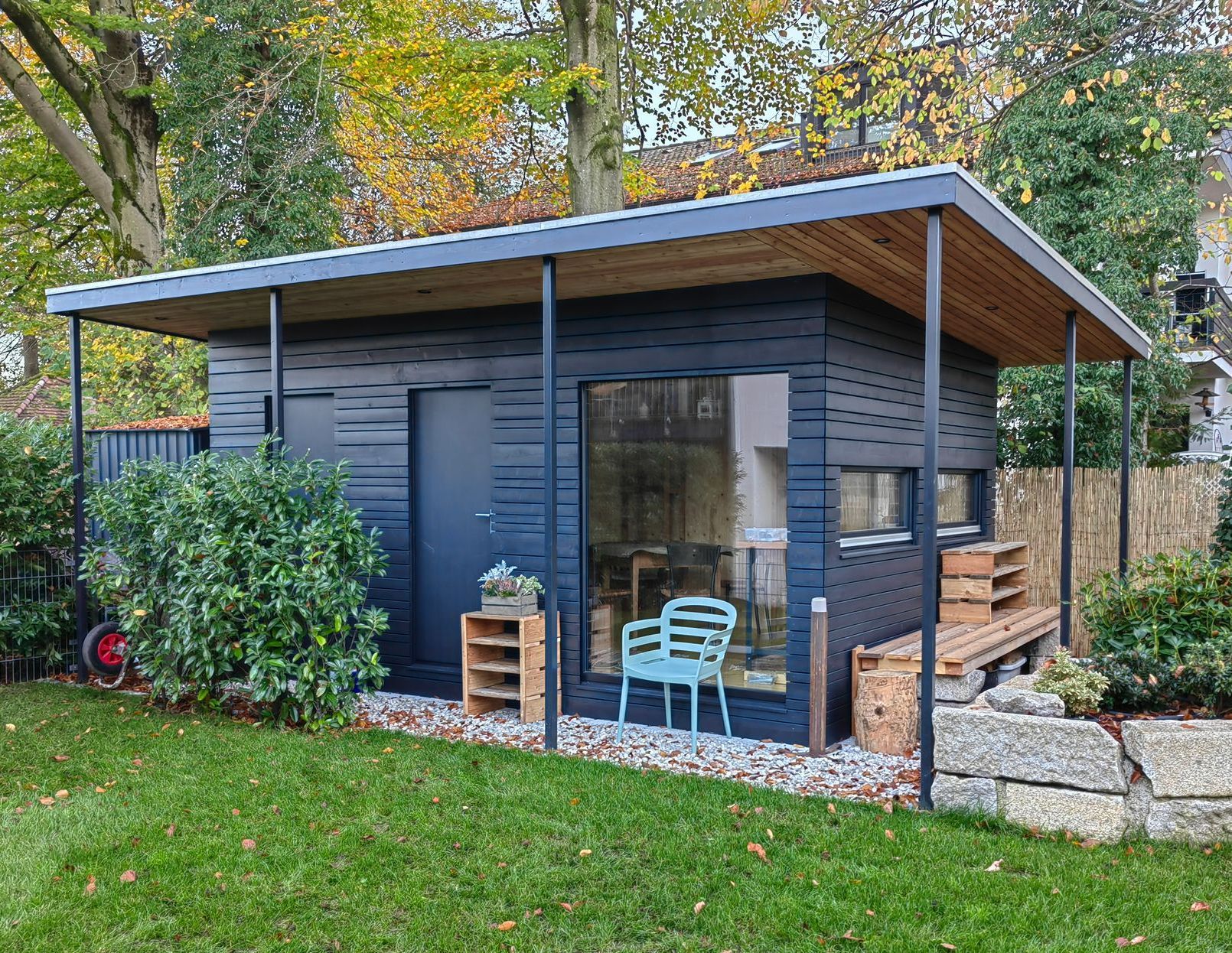 Modernes Gartenhaus im Mid-Century-Stil mit Flachdach und dunkler Holzfassade-realisiert von Zimmerei bauwerk singer in München