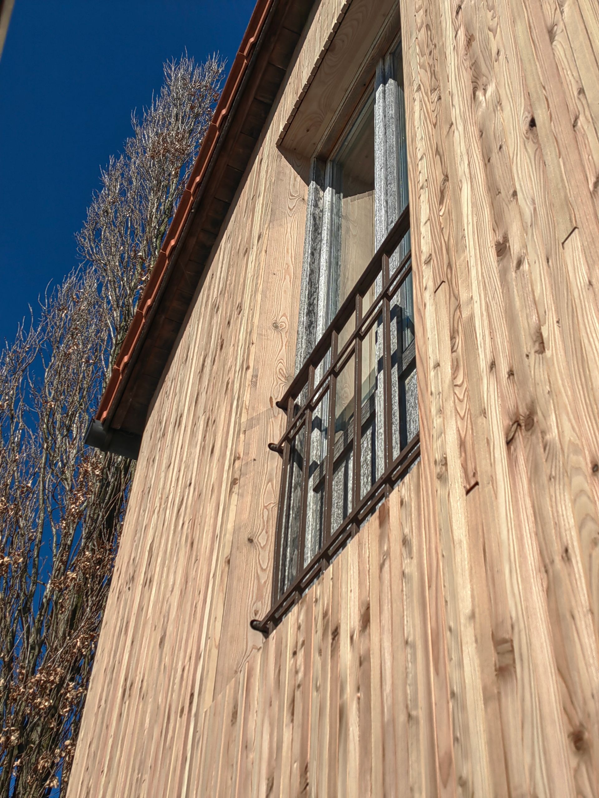 Detailansicht einer modernen Holzfassade mit vertikaler Lärchenverschalung - Fassadensanierung in München
