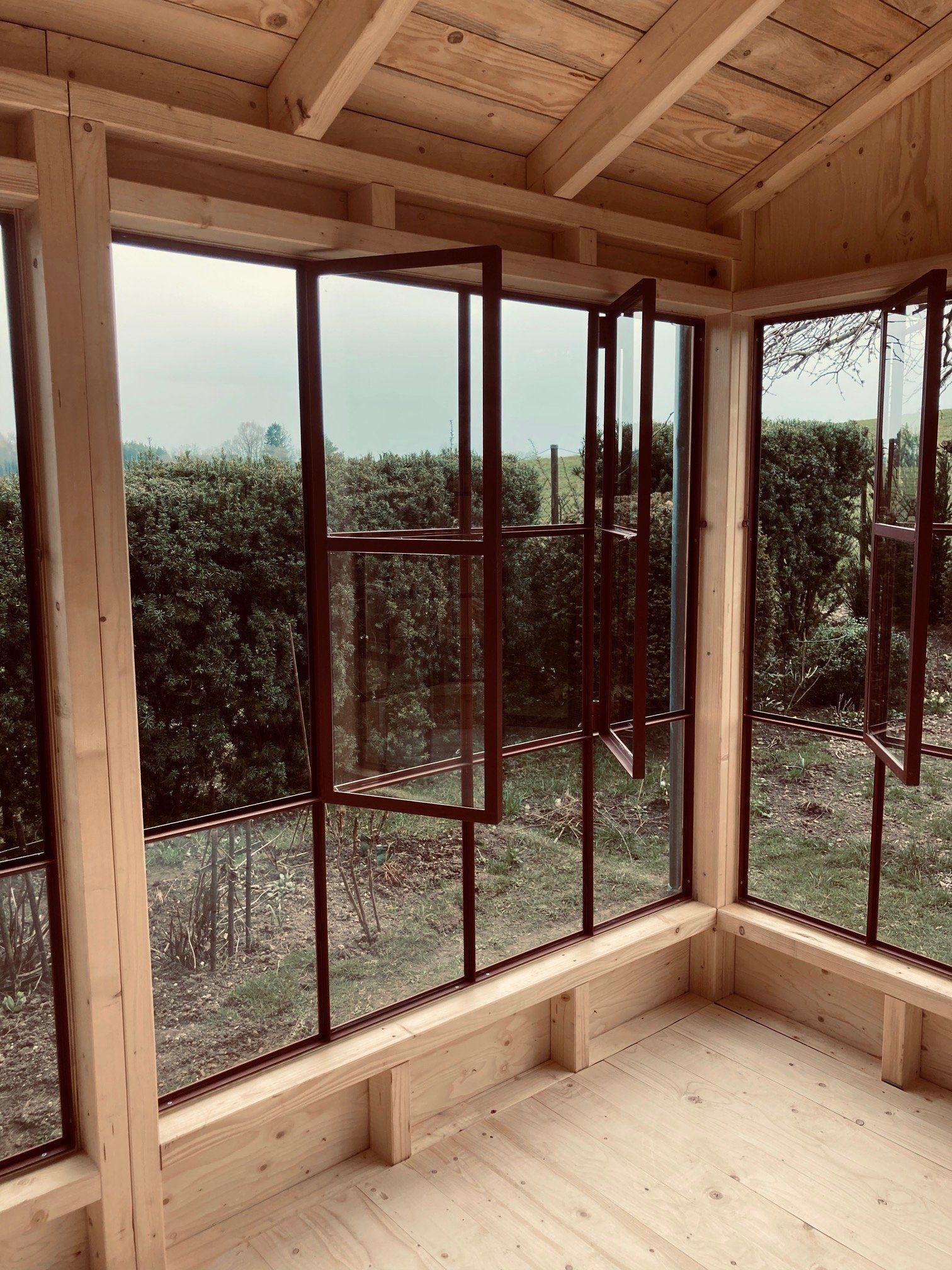 Innenansicht einer lichtdurchfluteten Orangerie mit Blick auf den Garten im Chiemgau