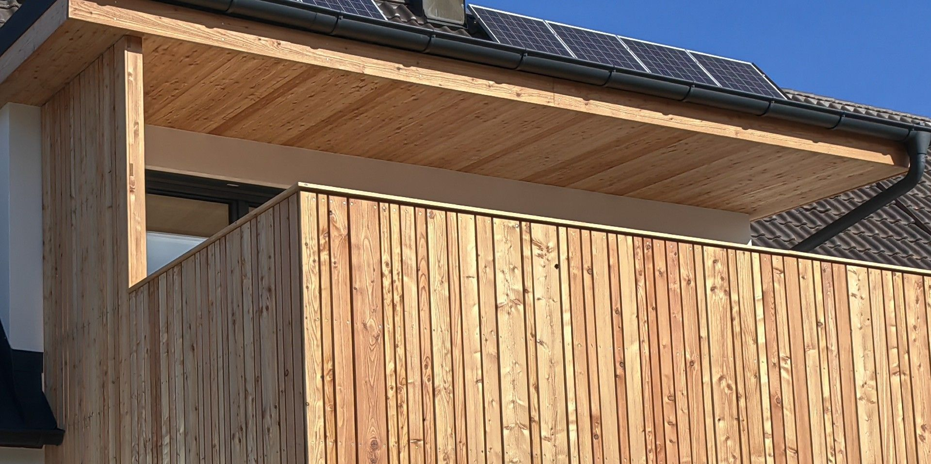 Individuelle Dachgaube mit vorgelagerter Holzterrasse und klarer Konstruktion aus Holz
