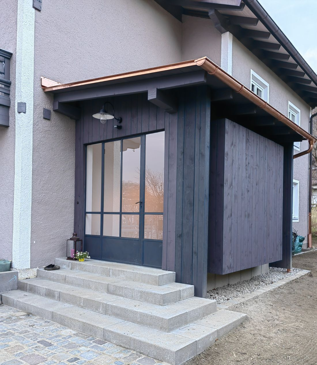 Moderner Eingangsbereich aus Holz mit Überdachung und Holzfassade im Raum Rosenheim