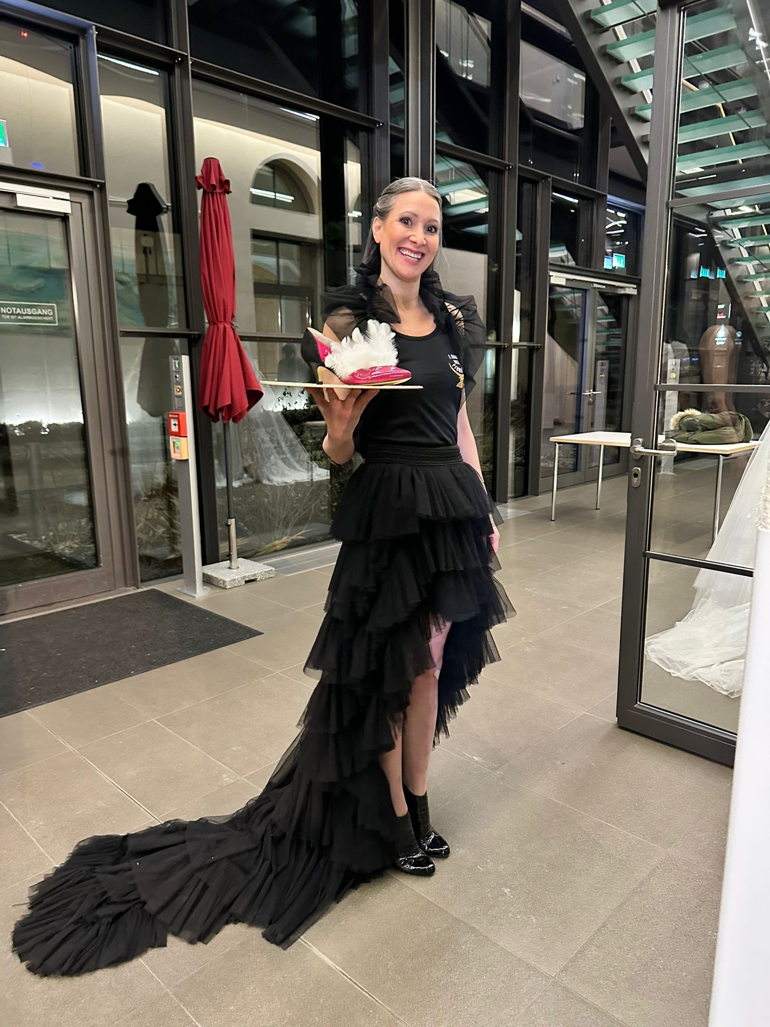 Karin Wadle in einem Outfit und Highheels von Zarini. Pumps mit Federn auf dem Tablett.