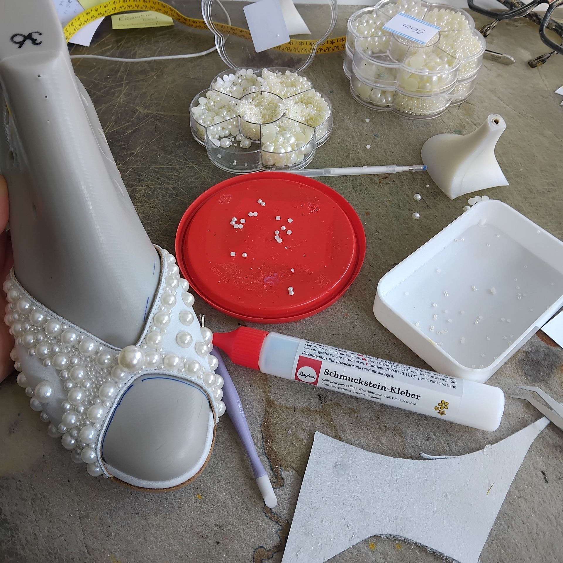 Die Perlenreihen auf den Brautschuhen werden mit kleineren Perlen aufgefüllt-Zarini