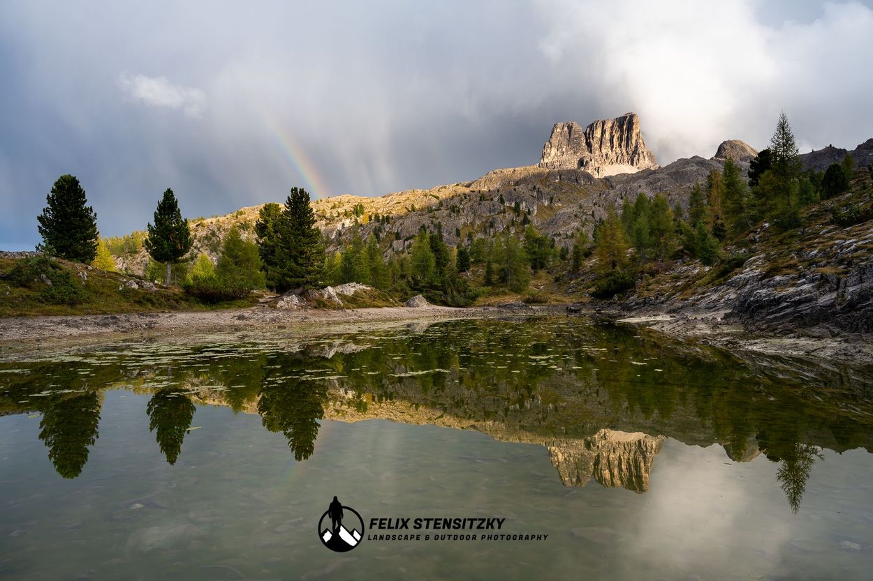 Landschaftsfoto von einem See in den Dolomiten mit Spiegelung und Regenbogen