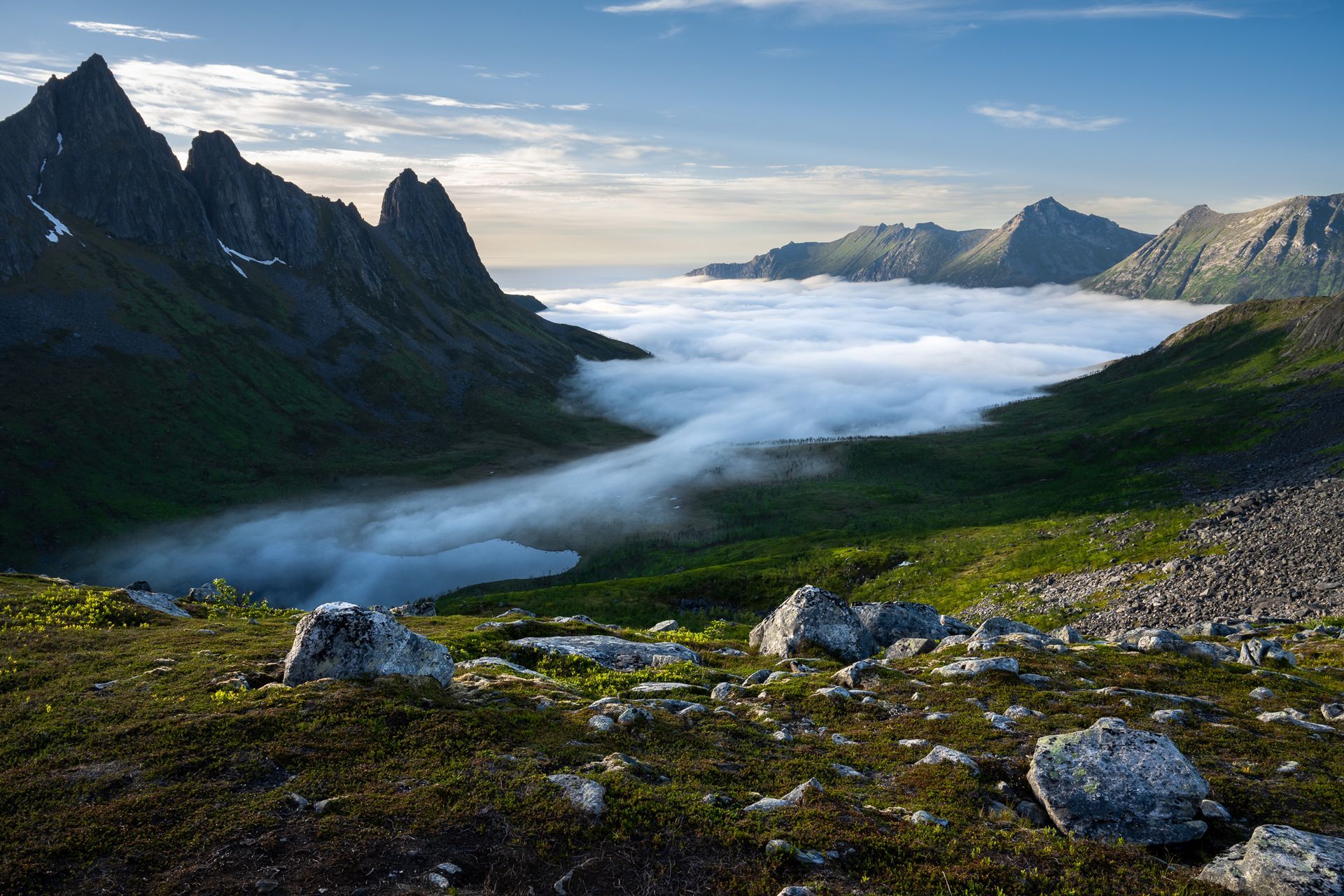 ein Ausblick auf der Insel Senja mit steilen Bergen und einem Tal mit Wolken gefüllt