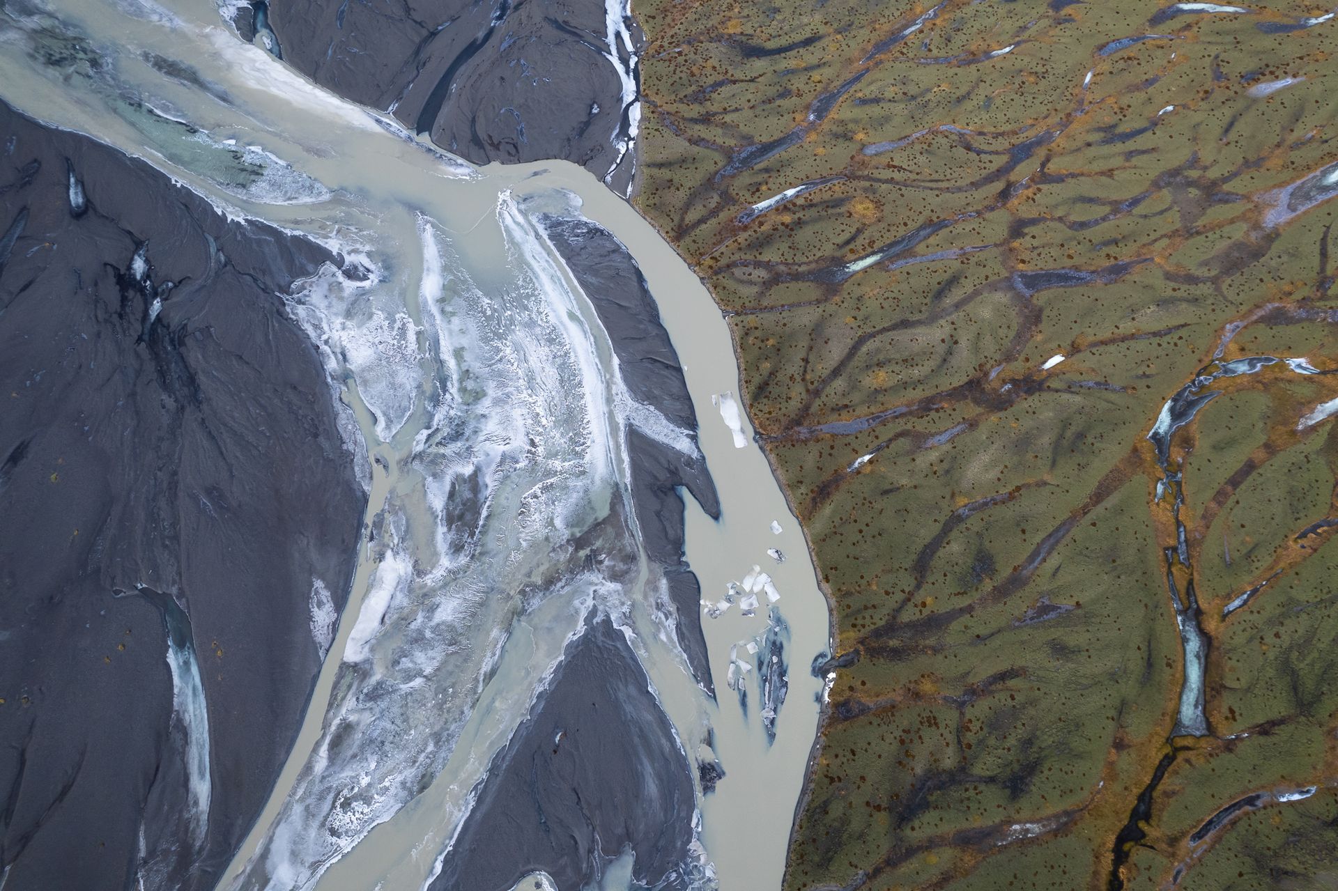 Abstrakte Luftaufnahme eines Flusses der die Landschaft in schwarz und grün aufteilt