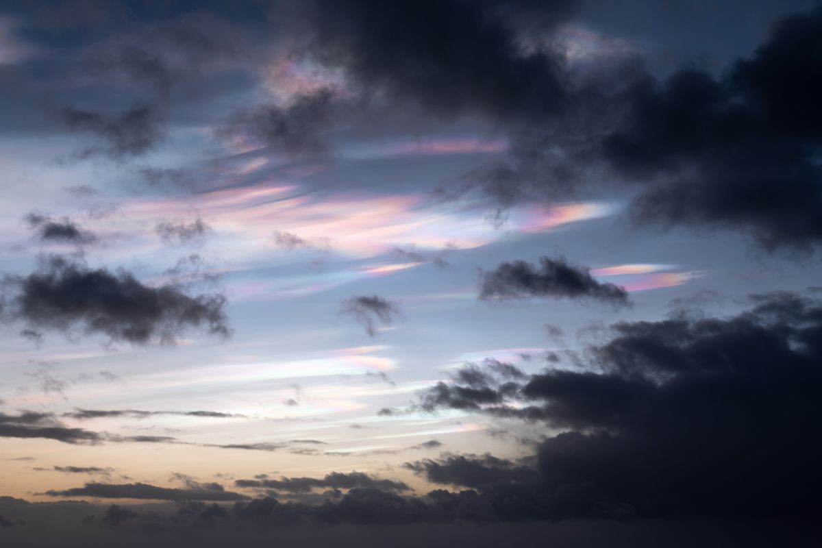 picture of colourful glowing polar stratospheric clouds with dark clouds in front
