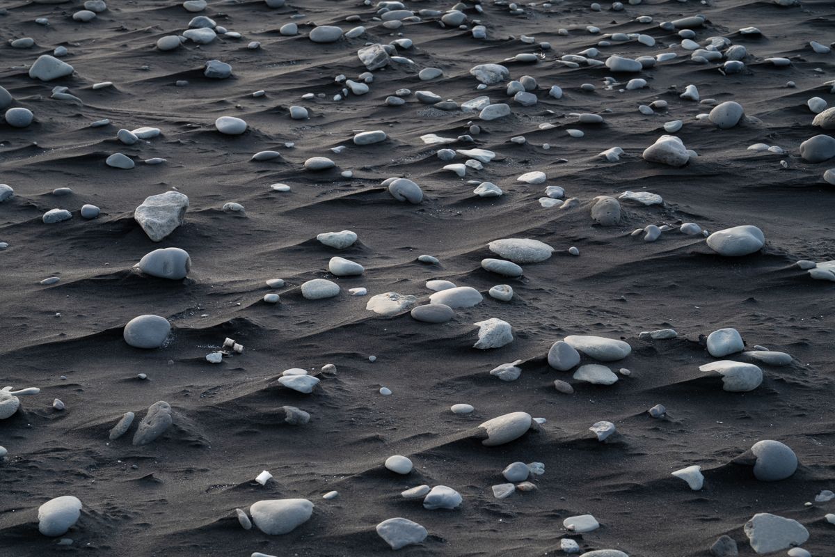 Detailaufnahme von Steinen und schwarzem Sand am Strand
