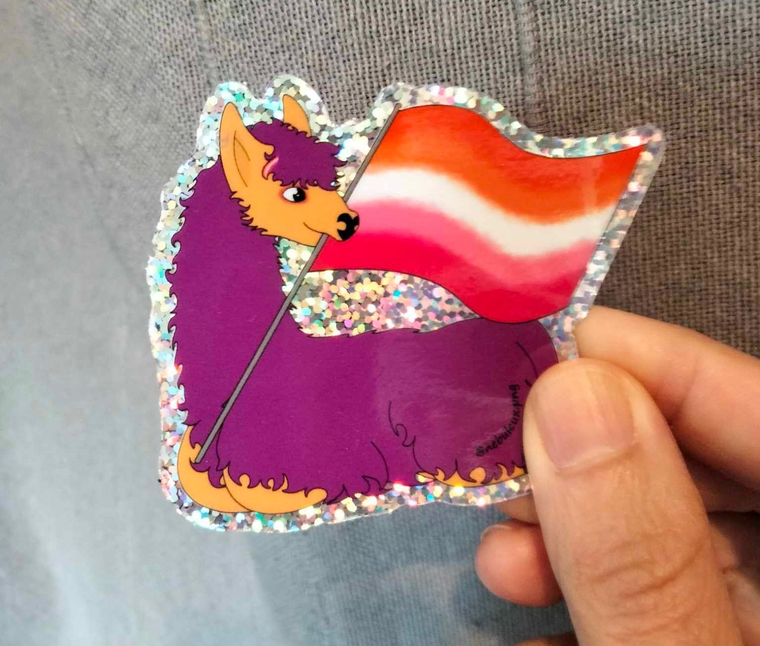 Barbouille le lama avec le drapeau lesbien Illustration de Barbouille tenant un drapeau lesbien avec 5 bandes de couleurs. Une orange foncée, une orange, une blanche, une violette, une violette foncée.