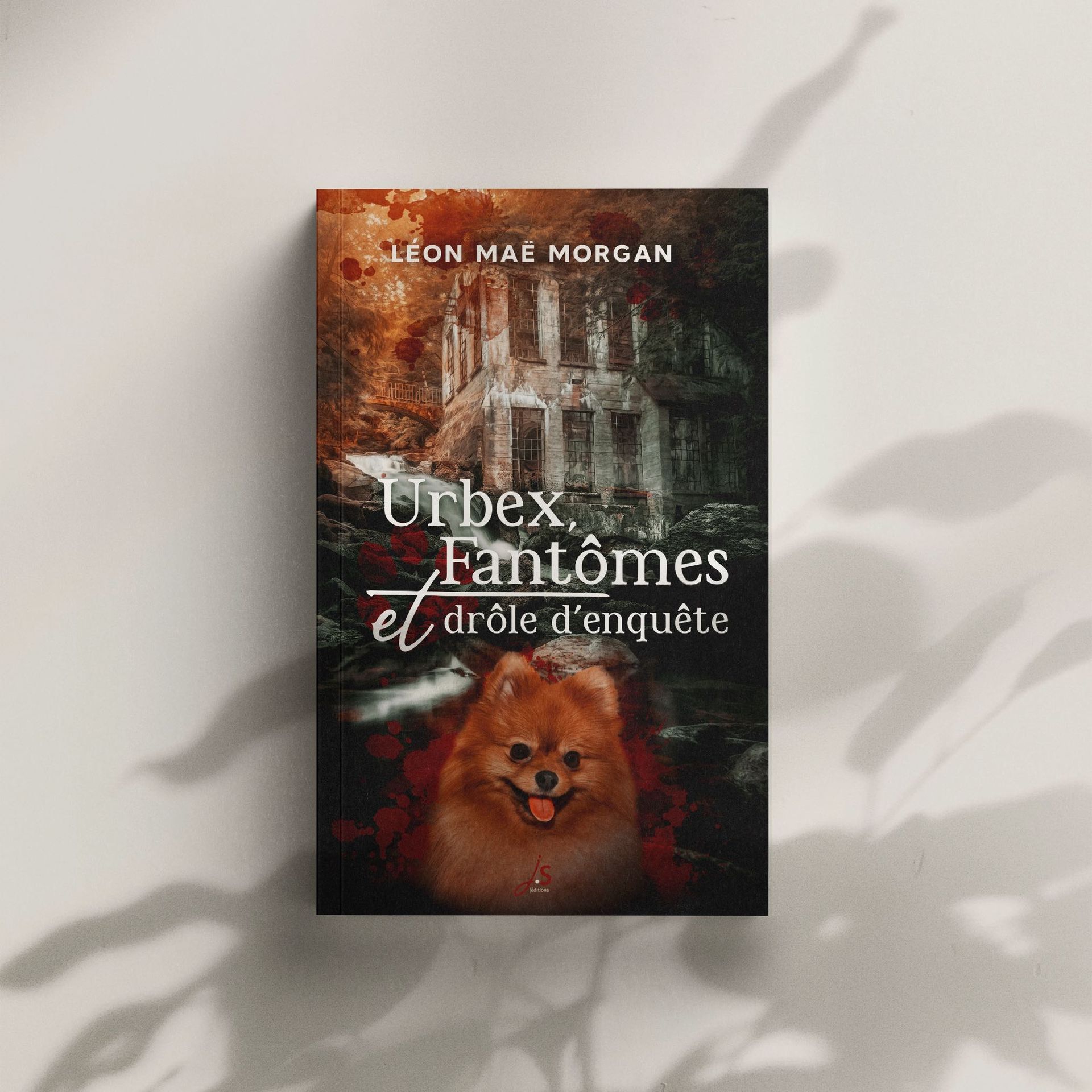 Le roman Urbex, fantômes et drôle d'enquête sur un fond clair avec une ombre de plante. La couverture montre un lieu d'urnes en forêt et un chien spitz nain collé sur une projection de gouttes de sang