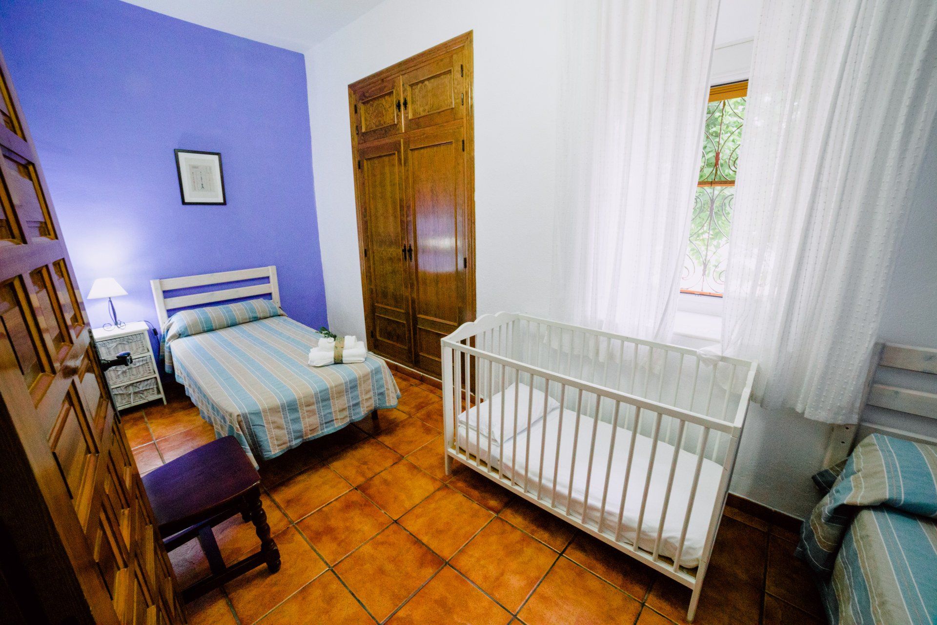 Dormitrio para dos persona con cuna de bebe en la